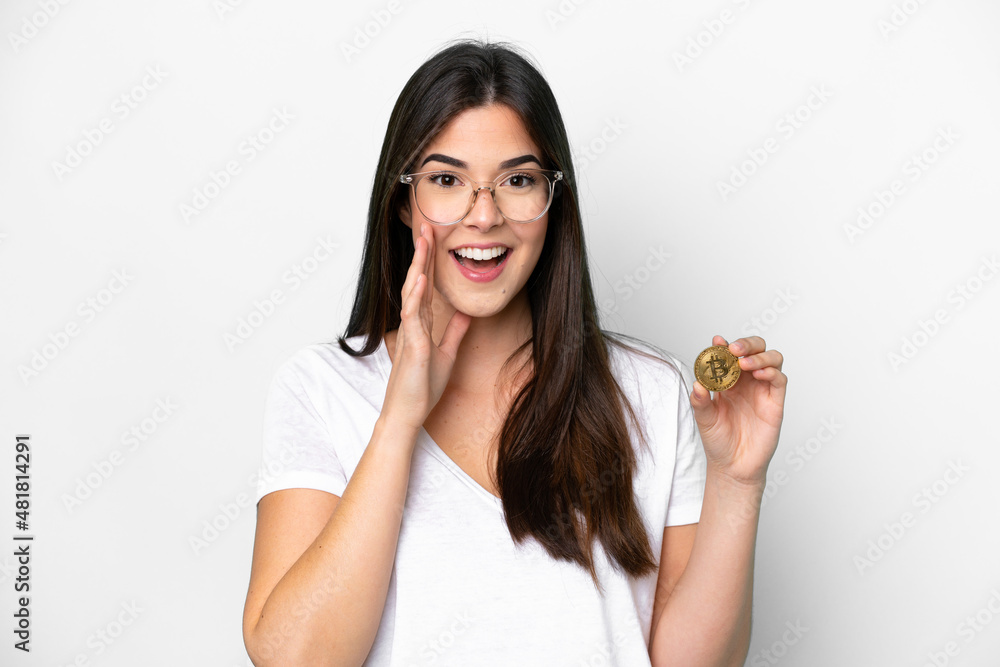 Young Brazilian woman holding a Bitcoin isolated on white background shouting with mouth wide open Young Brazilian woman holding a Bitcoin isolated on white background shouting with mouth wide open