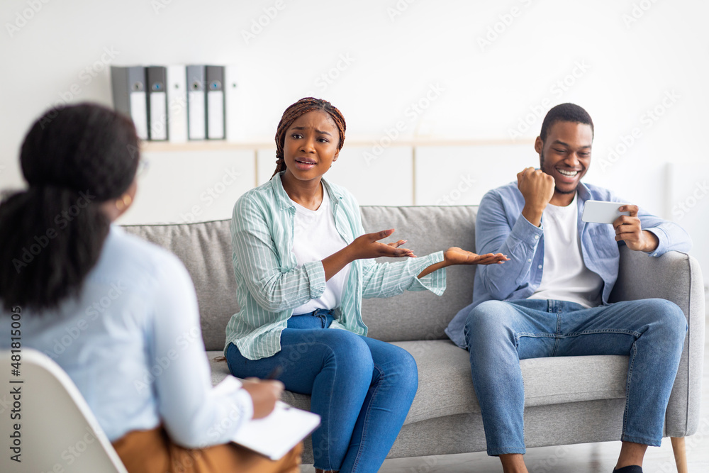 © Prostock-studio - Annoyed black woman complaining about her boyfriend's smartphone overuse during psychological consultation at clinic © Prostock-studio - Annoyed black woman complaining about her boyfriend's smartphone overuse during psychological consultation at clinic