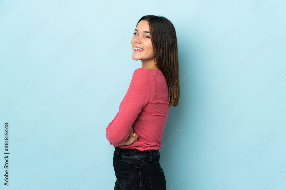 Teenager girl isolated on blue background with arms crossed and happy Teenager girl isolated on blue background with arms crossed and happy