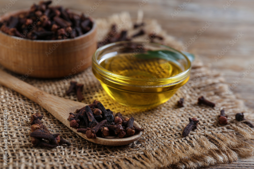 Essential oil and dried cloves on wooden table, closeup Essential oil and dried cloves on wooden table, closeup