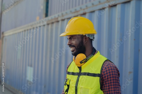 Smiley African american cargo worker with safety helmet and vest outfit in import and export logistic shipping