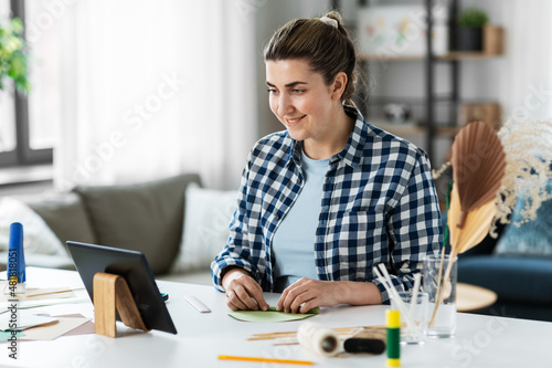 diy, art and hobby concept - happy smiling woman with tablet pc computer making paper craft at home