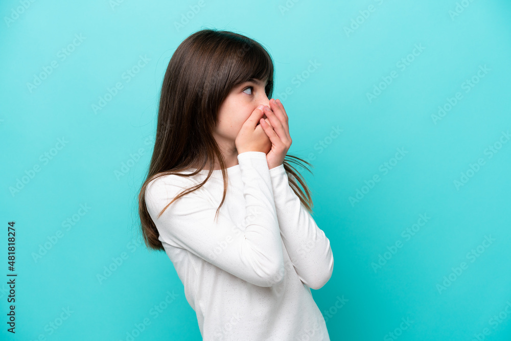 Little caucasian girl isolated on blue background covering mouth and looking to the side Little caucasian girl isolated on blue background covering mouth and looking to the side