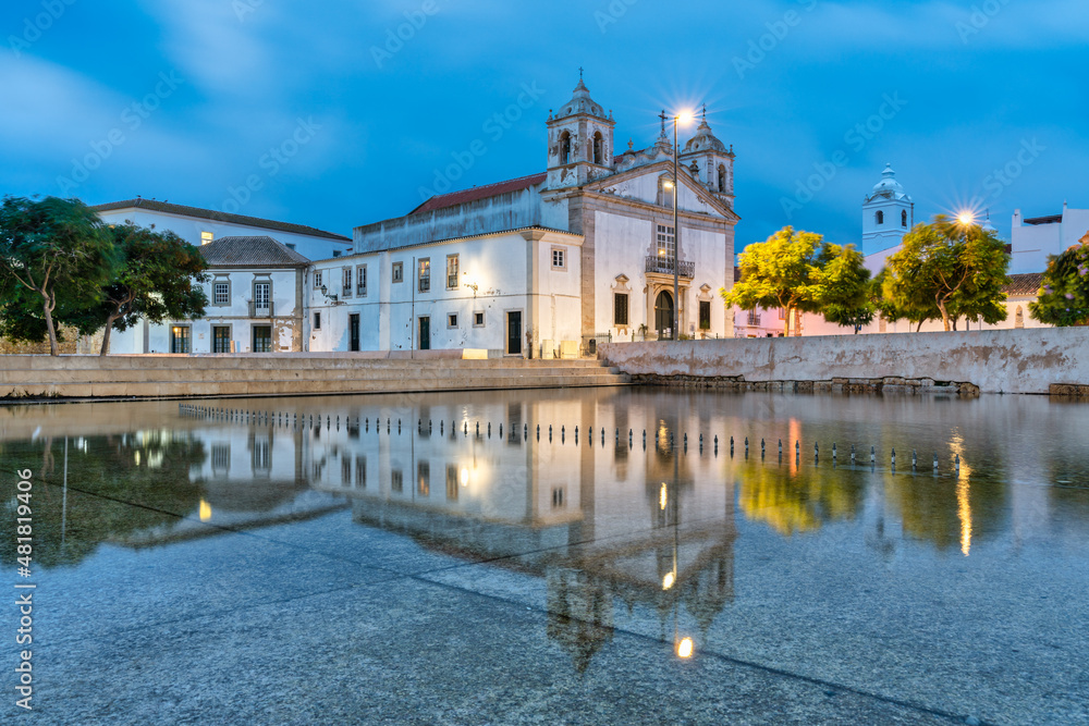 view of the main square of Lagos in Portugal with the church of Santa Maria reflected in water from the fountain