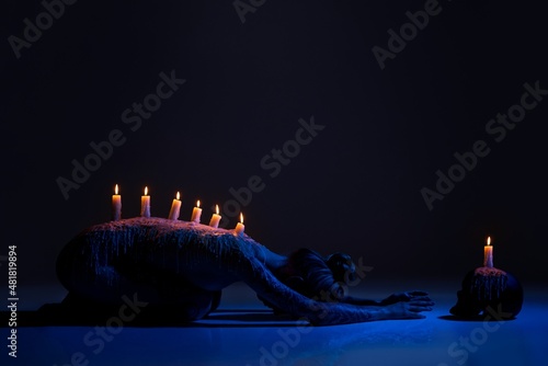 Fotografie, Obraz Burning candles on back of lady bowing down in darkness