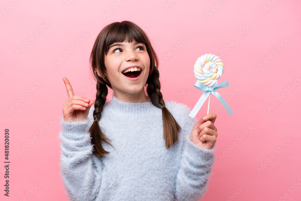 Little caucasian girl holding a lollipop thinking an idea pointing the finger up Little caucasian girl holding a lollipop thinking an idea pointing the finger up