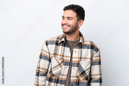 Young Brazilian man isolated on white background looking to the side and smiling