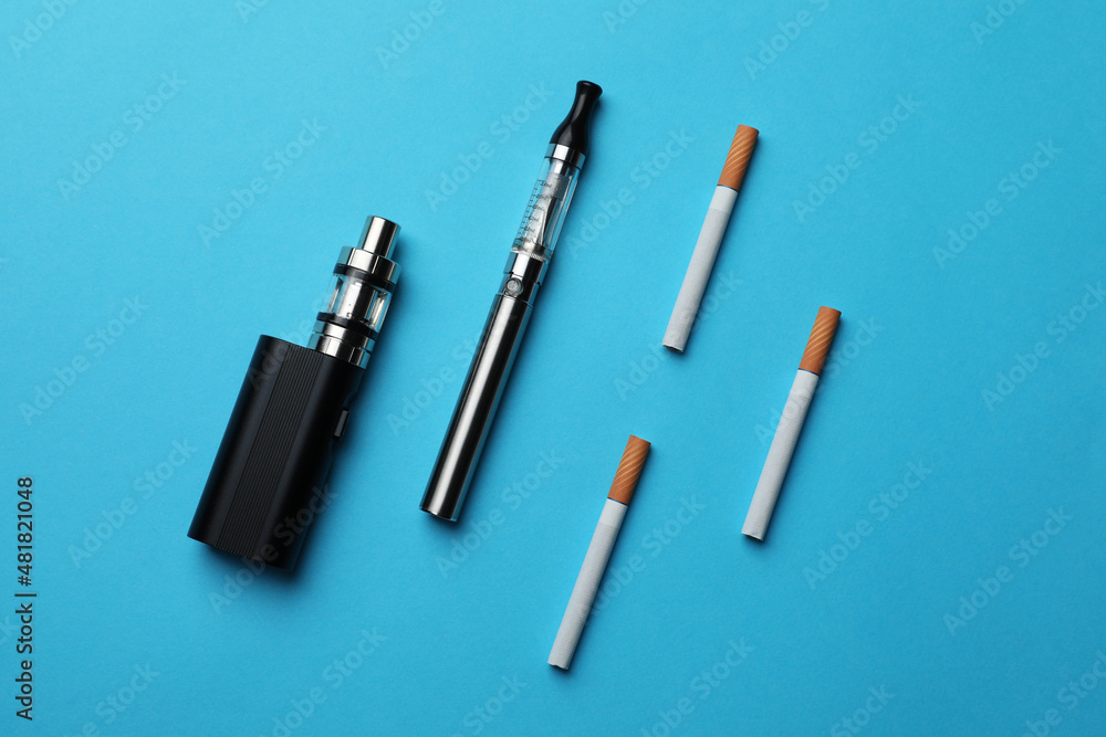 Electronic and regular cigarettes on light blue background, flat lay