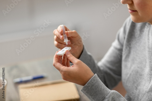 medicine, quarantine and pandemic concept - close up of woman making self testing coronavirus test at home photo