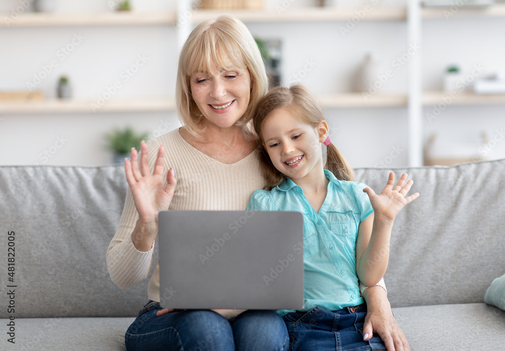 Granny and girl having videocall using laptop waving hands Granny and girl having videocall using laptop waving hands