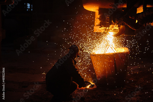 Metallurgist steelmaker takes a sample of liquid metal from a ladle. Ingot casting. Steel production. Metallurgy. Industry