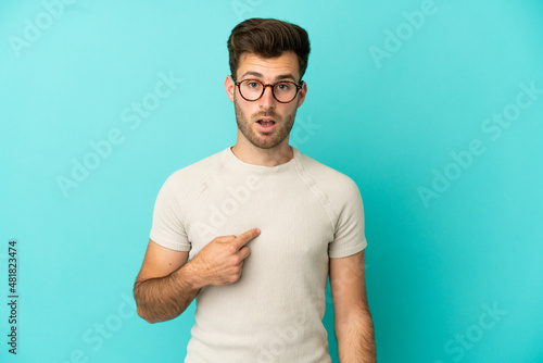 Young caucasian handsome man isolated on blue background pointing to oneself