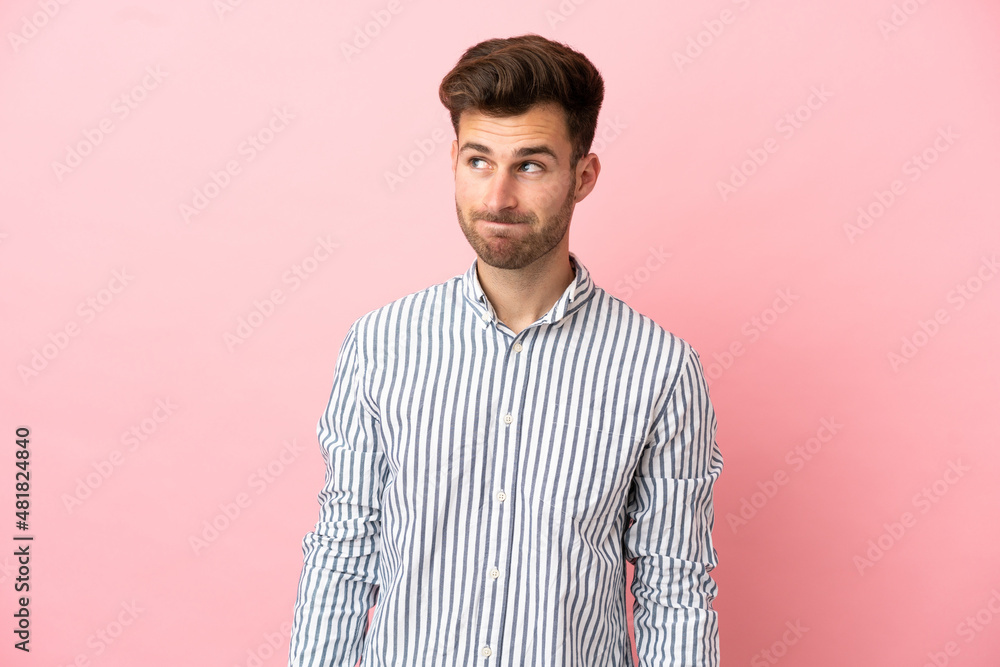 Young caucasian handsome man isolated on pink background having doubts while looking up Young caucasian handsome man isolated on pink background having doubts while looking up