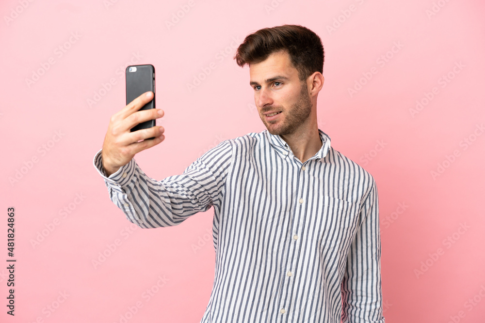 Young caucasian handsome man isolated on pink background making a selfie Young caucasian handsome man isolated on pink background making a selfie