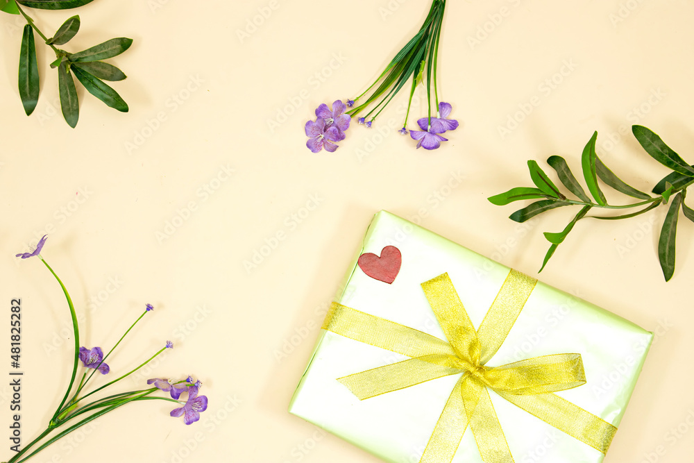 happy valentine's  or mother's day  concept. small red wooden heart on gift decorated with yellow ribbon and flowers isolated on pink background