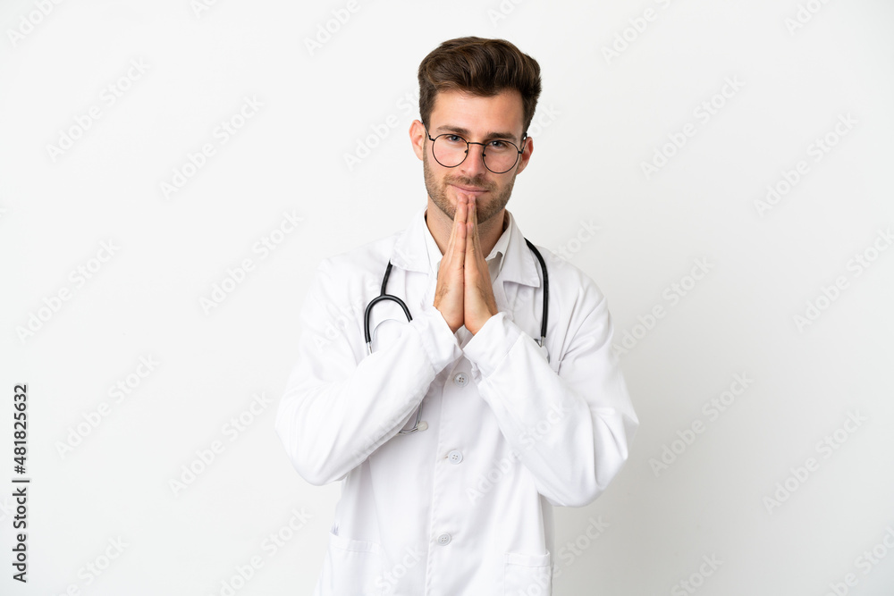 Young doctor caucasian man over isolated on white background wearing a doctor gown and pleading Young doctor caucasian man over isolated on white background wearing a doctor gown and pleading