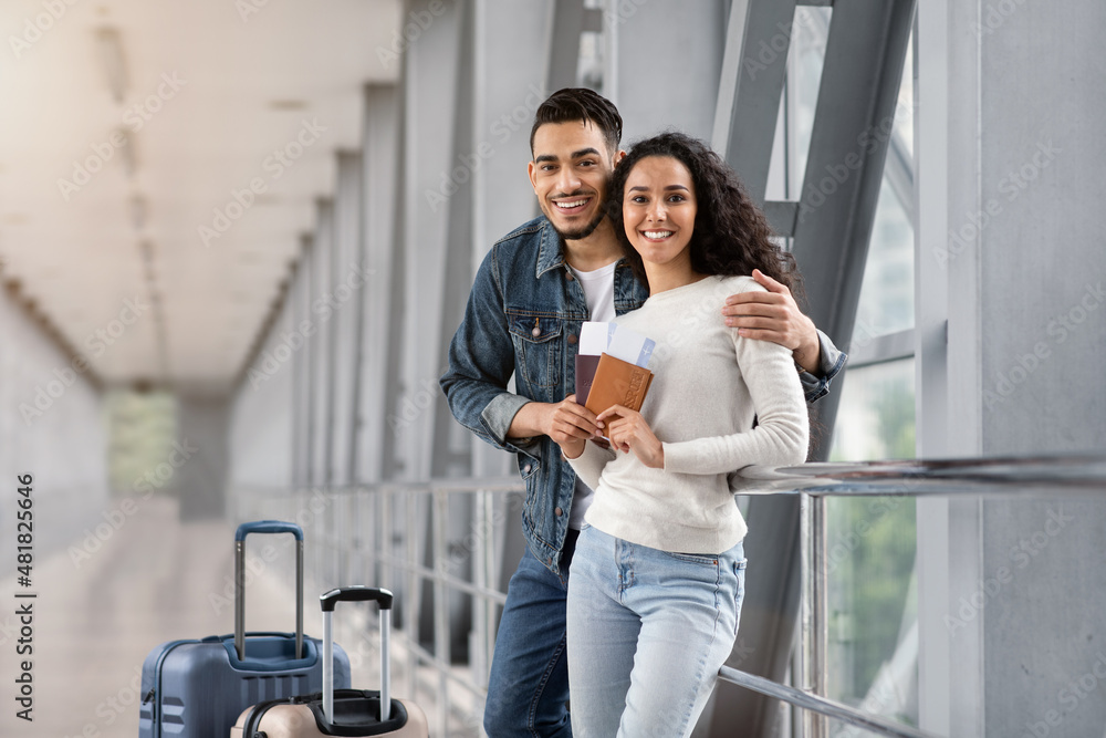 Happy Arab Spouses Posing In Airport Terminal, Looking At Camera And Smiling