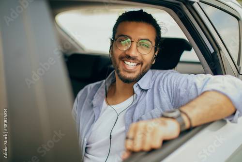 Stylish arab guy travelling by car service, listening to music © Prostock-studio