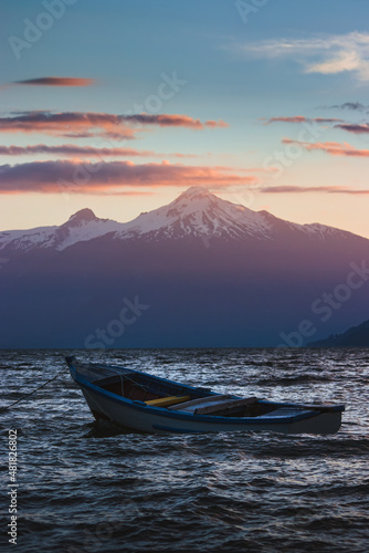 Lonely boat at sunset with mountains in the background