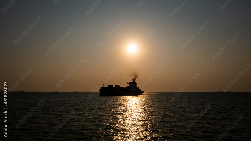 Silhouette Container ship full load carrying for import and export, business cargo logistic and transportation by container ship in open sea over the sunlight background,