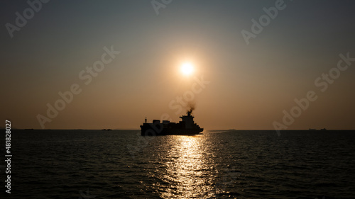 Silhouette Container ship full load carrying for import and export, business cargo logistic and transportation by container ship in open sea over the sunlight background, © SHUTTER DIN