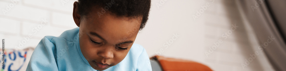 Black boy paying with toys while sitting on sofa at home Black boy paying with toys while sitting on sofa at home
