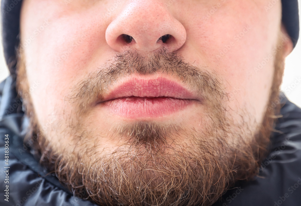 Face of a young man with messy and untrimmed beard and moustache close-up. Selective focus. Outdoors