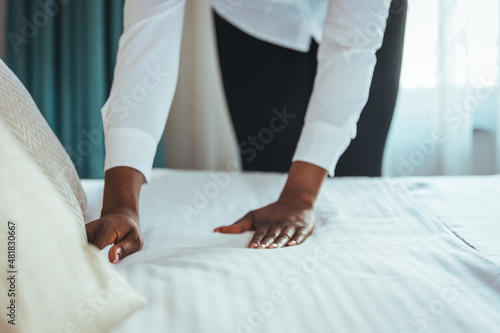 Maid making bed in hotel room. Housekeeper Making Bed. Maid making bed in hotel room. Staff Maid Making Bed. African housekeeper making bed.