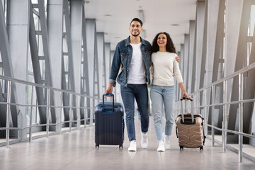 Ready For Vacation. Romantic Middle-Eastern Couple Walking With Suitcases At Airport Terminal