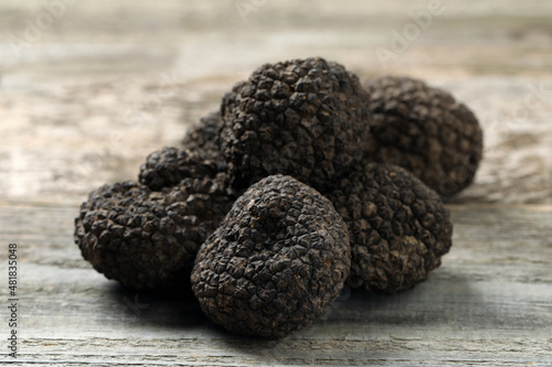 Heap of black truffles on wooden table, closeup