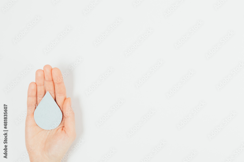 Naklejka premium Hand holds drop of clean water on white background
