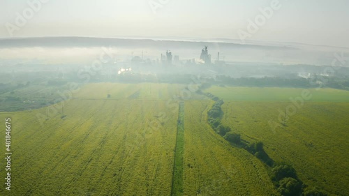 A sunflower field shot by a copter, beautiful flowers and a useful agricultural crop - for the food and technical industries. Against the backdrop of a food processing plant. photo