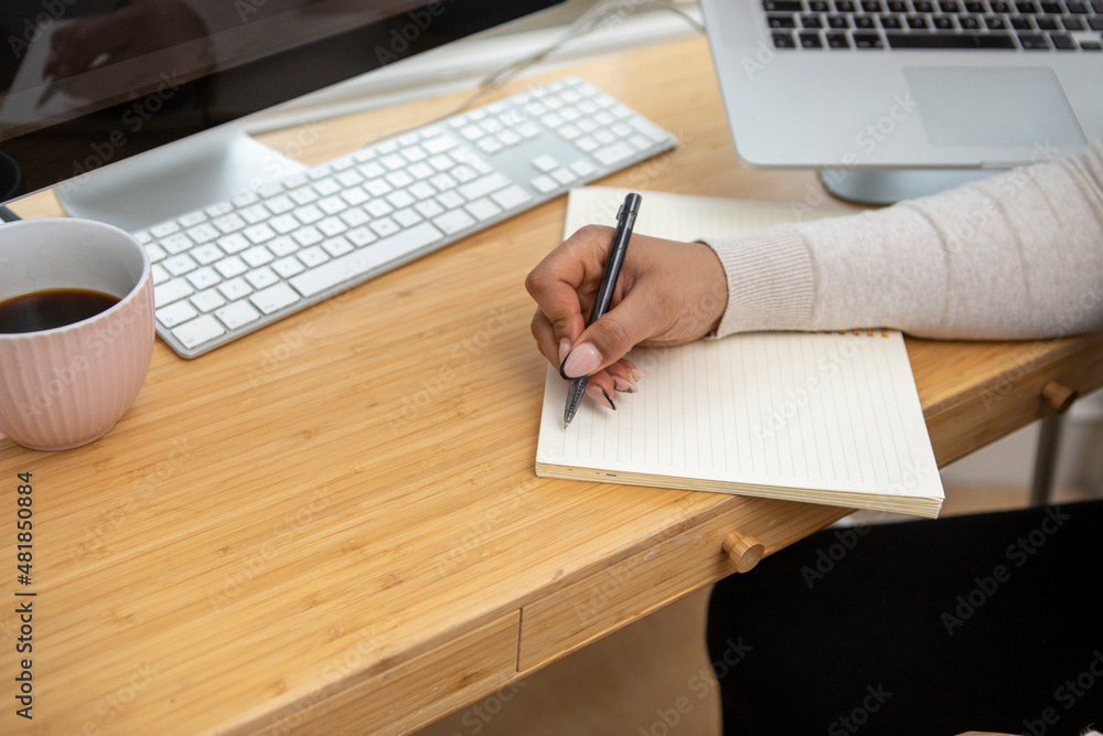 Close-up of woman writing in notebook at desk Close-up of woman writing in notebook at desk
