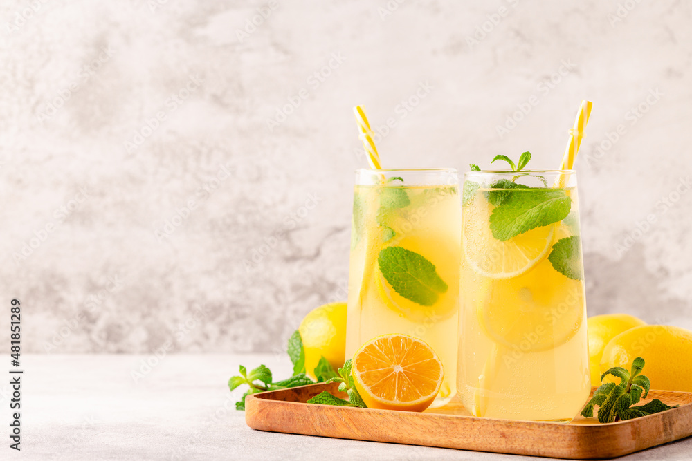 Fototapeta premium Lemonade with lemon, mint and ice cubes in glass