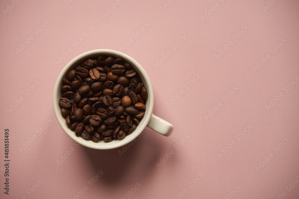 Naklejka premium ziarna kawy w białej filiżance na różowym tle
