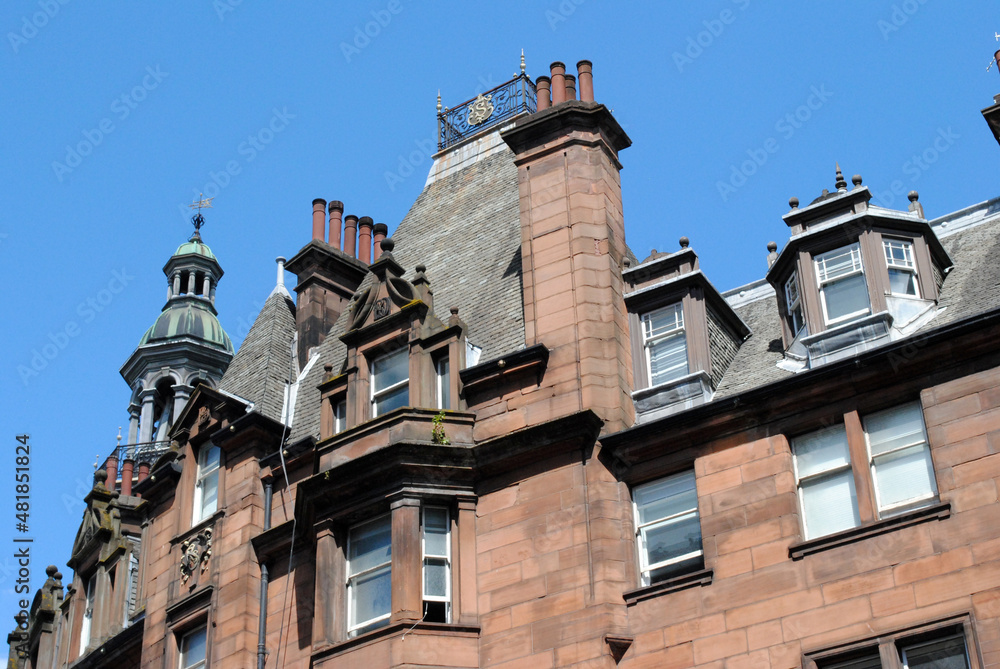 Detailed Skyline of Chimneys and Cupolas on 19th Century Buildings seen from Below against Blue Sky
