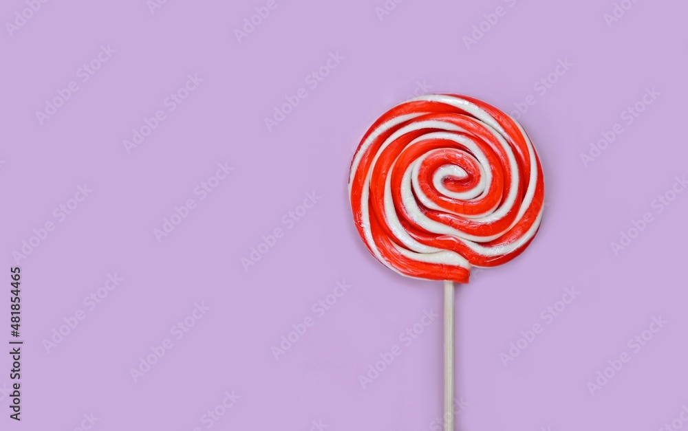 Round white and red lollipop with wooden stick on lilac background. Round white and red lollipop with wooden stick on lilac background.