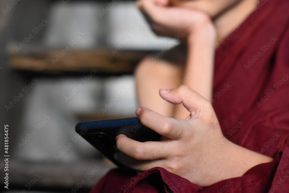 Asian little monk watching mobile smart phone. Concept of screen time.