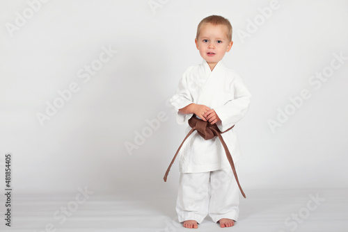 Little baby boy in karate kimono isolated on white background. The concept of martial arts, karate, judo,  sports since childhood, discipline. Defence concept with copy space.