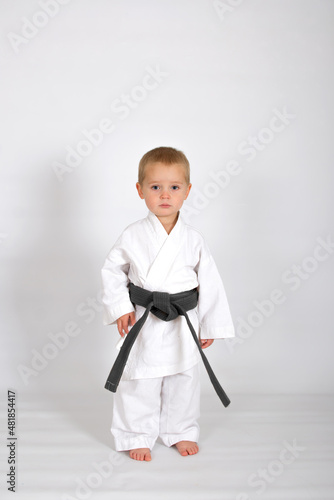 Little baby boy in karate kimono isolated on white background. The concept of martial arts, karate, judo,  sports since childhood, discipline. Defence concept with copy space.