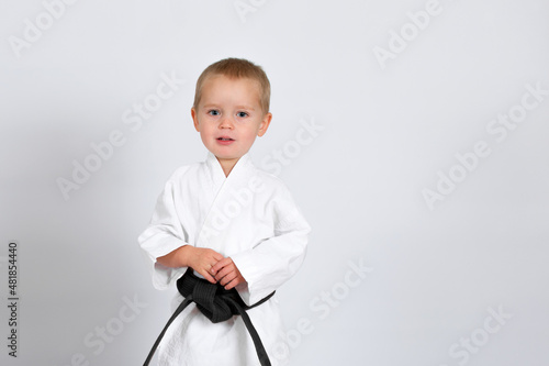 Little baby boy in karate kimono isolated on white background. The concept of martial arts, karate, judo,  sports since childhood, discipline. Defence concept with copy space.