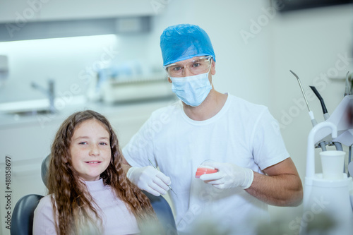 Fotografi Portrait of a male dentist and his patient, a cute Caucasian little girl