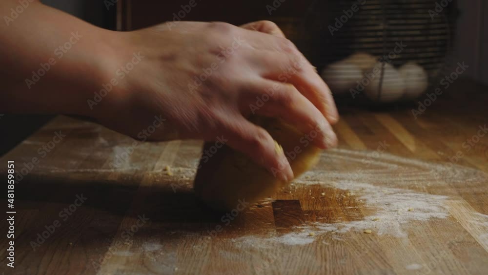 Hands knead a pasta dough or baking dough on a rustic kitchen table