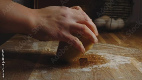 Hands knead a pasta dough or baking dough on a rustic kitchen table