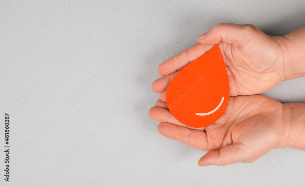 Holding a red drop in the hands, donate blood, world blood donor day