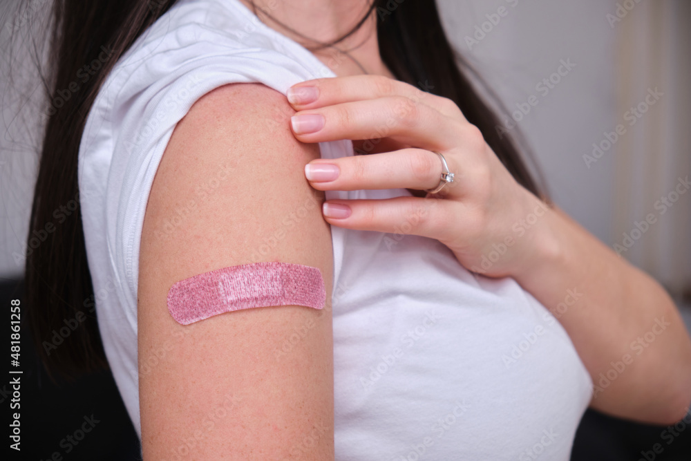 Woman with bandage on her arm after receiving vaccination, female after