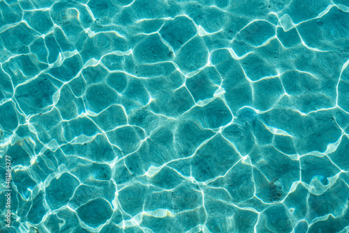 Clear water background. Top view of completely transparent turquoise sea water with sun reflections © GarkushaArt