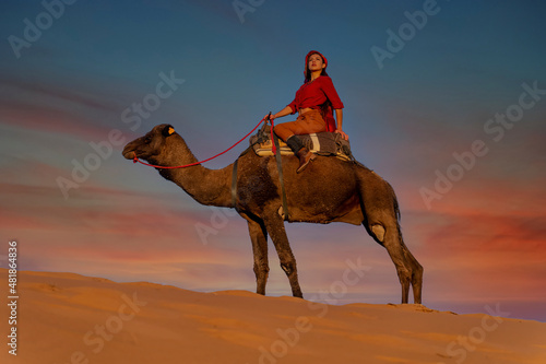 A Lovely Model Rides A Dromedary Camel Through The Saharan Desert On Their Camels In Morocco