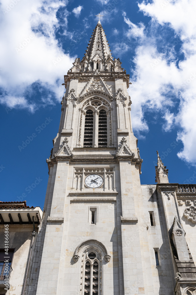 Front facade of Santiago Cathedral main tower in Bilbao old town under intense blue sky with clouds