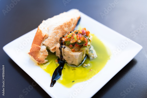 Traditional Spanish tapa made of tuna with bread slice, chopped peppers on top and olive oil. Restaurant bar snack on plate concept